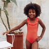Little girl wearing bright red one-piece swimsuit with ruffles on the back
