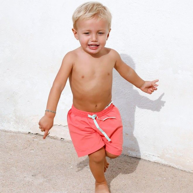 Little boy wearing Boys swim shorts in peach colour with light green elastic waistband